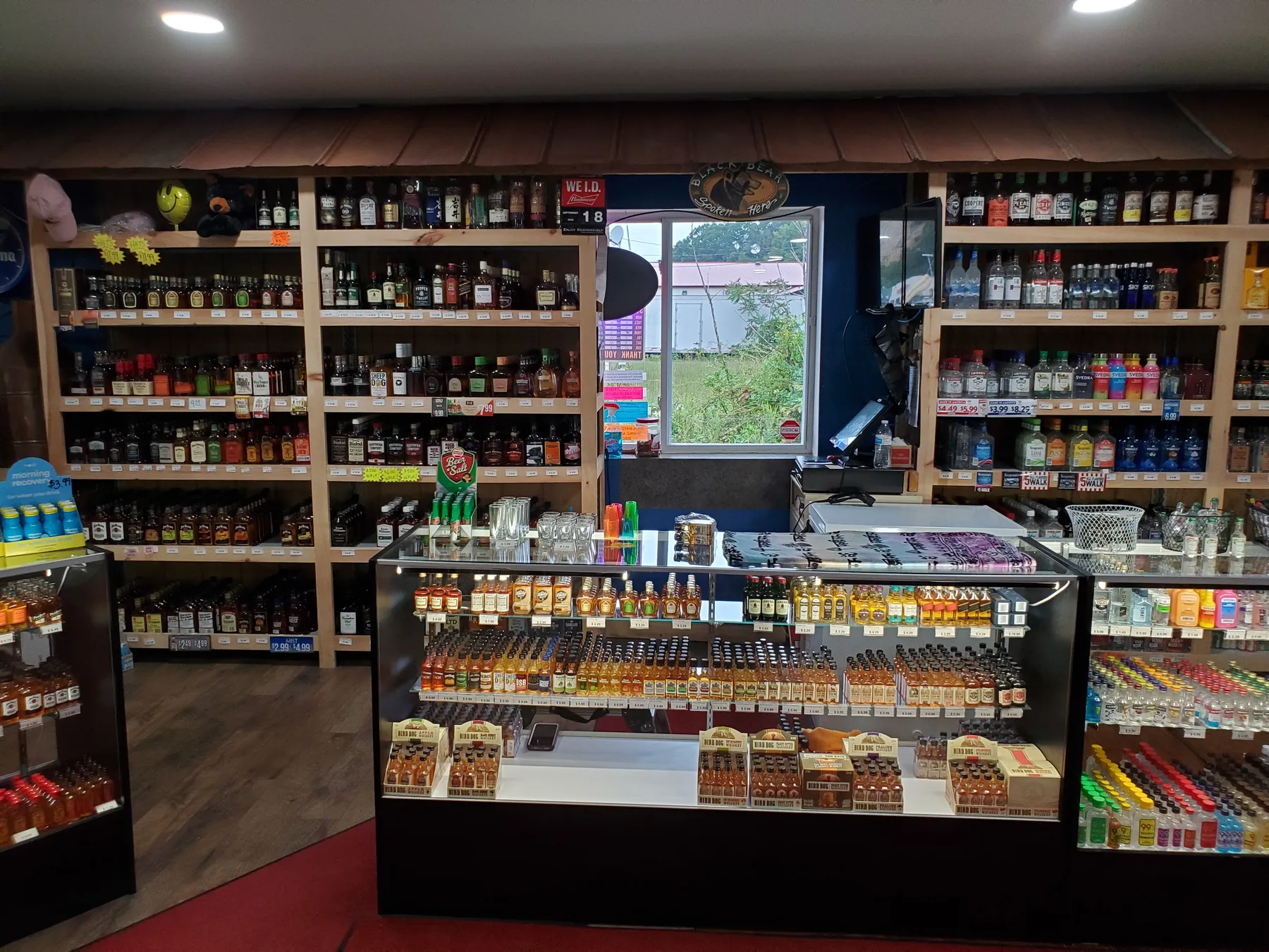 Wood shelves stocked with liquor around the drive-thru window
